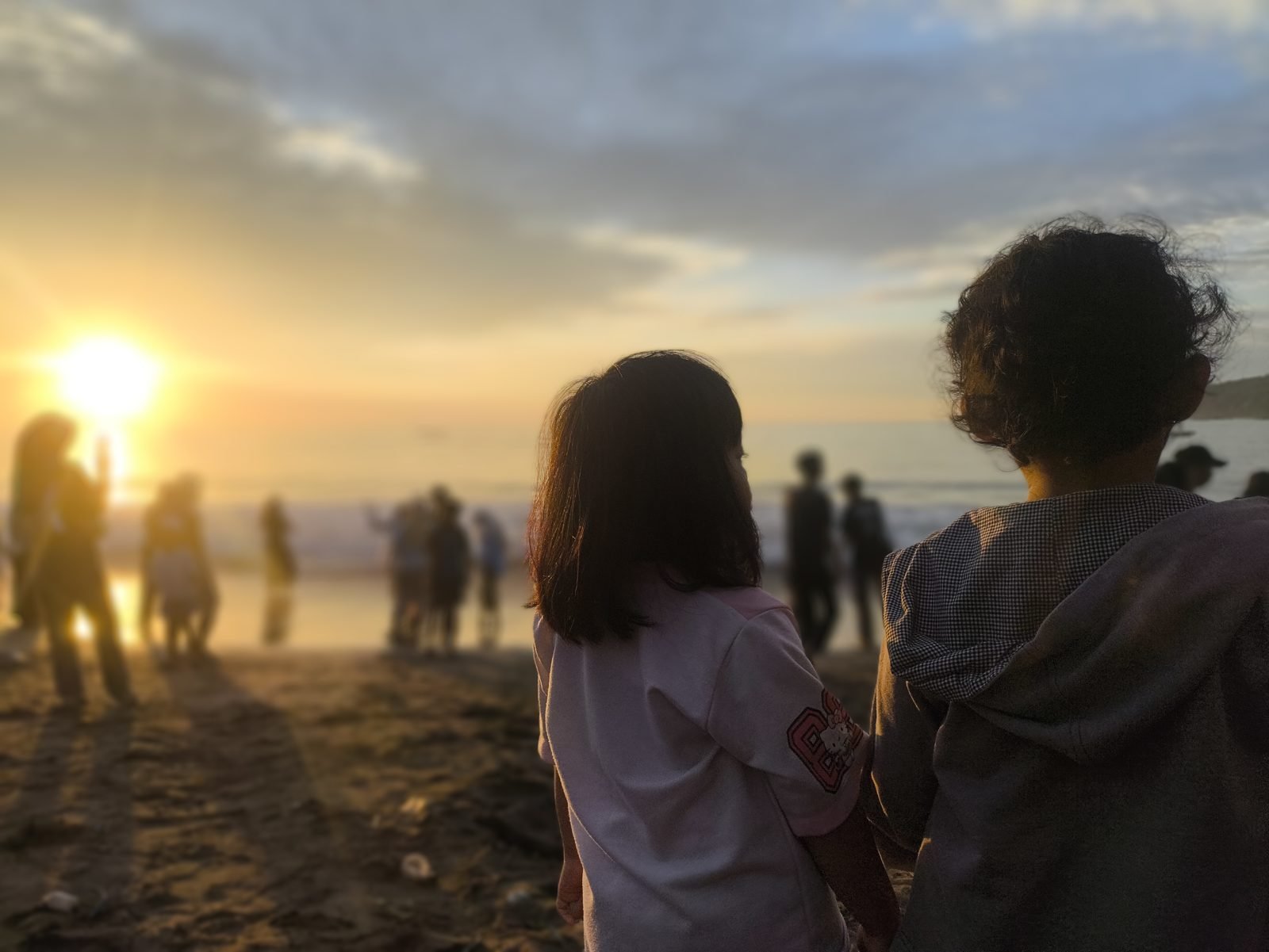 Looking at the light: two children watching sunrise at the beach